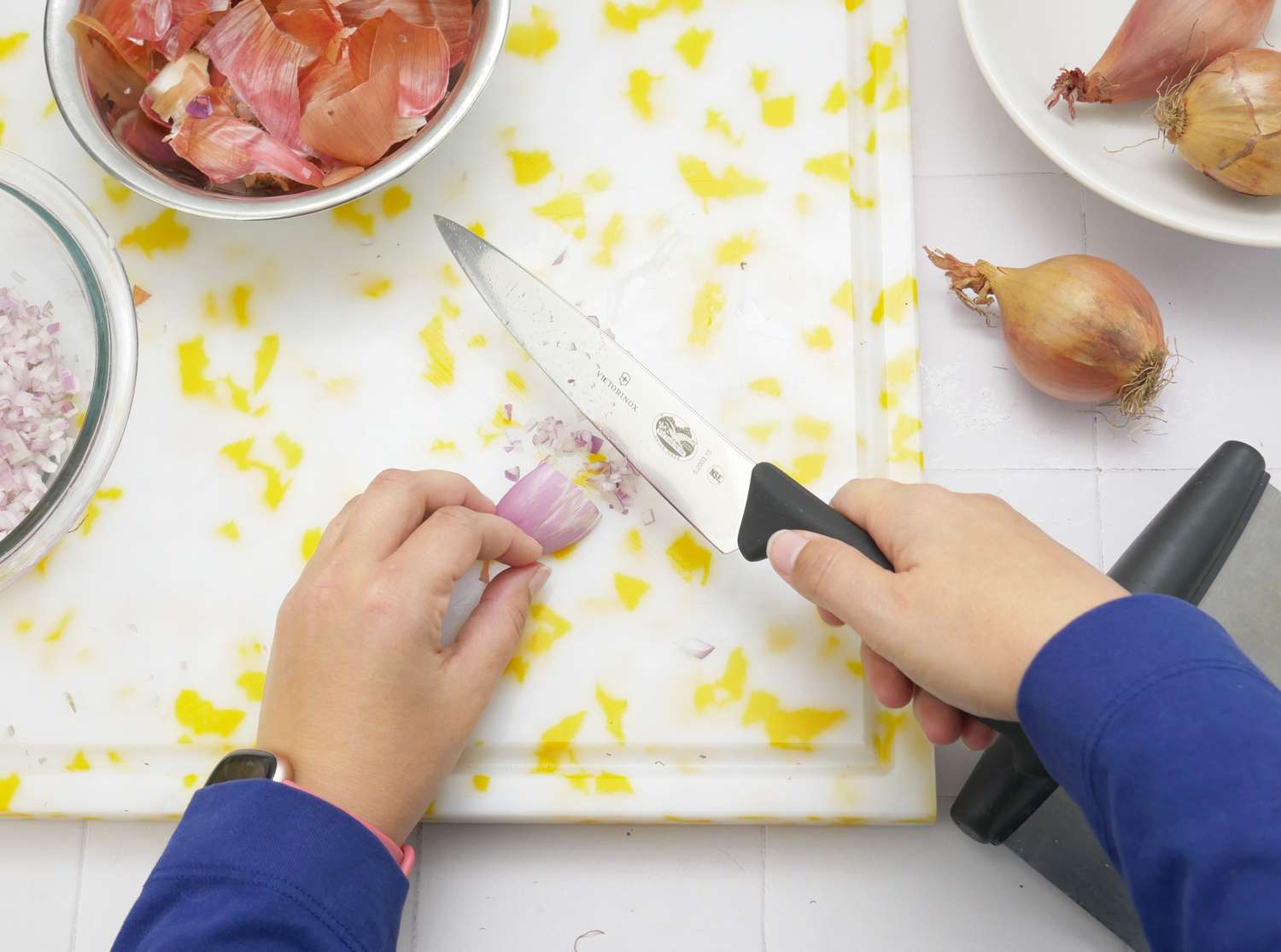 a person mincing shallots with a knife