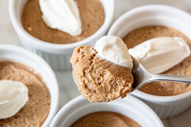 Bowls of pudding with whipped topping, spoon holding a serving