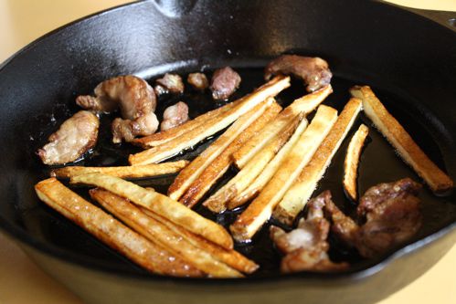 French fries and beef heart in a cast iron skillet.