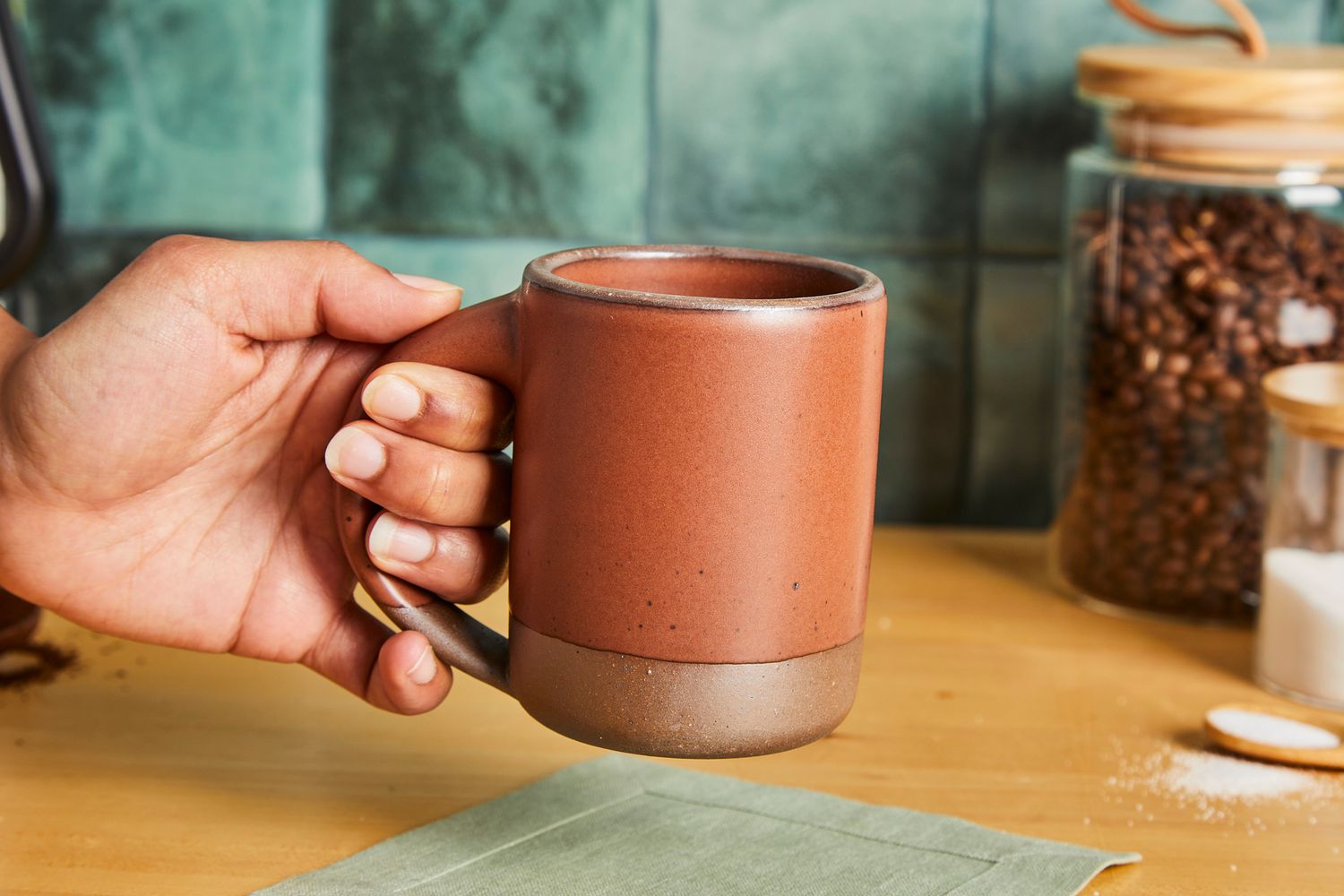 A person holding the handle of an East Fork coffee mug.