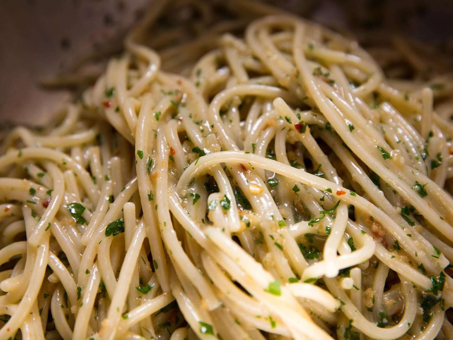 Closeup of spaghetti coated in the colatura sauce after tossing in a mixing bowl.