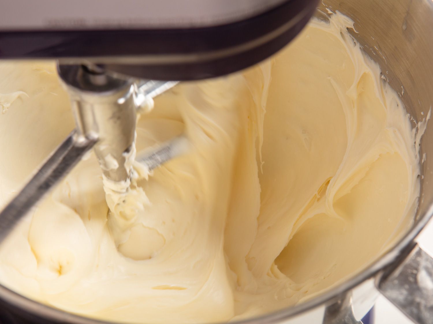 Cream cheese and sugar being mixed together in a stand mixer.
