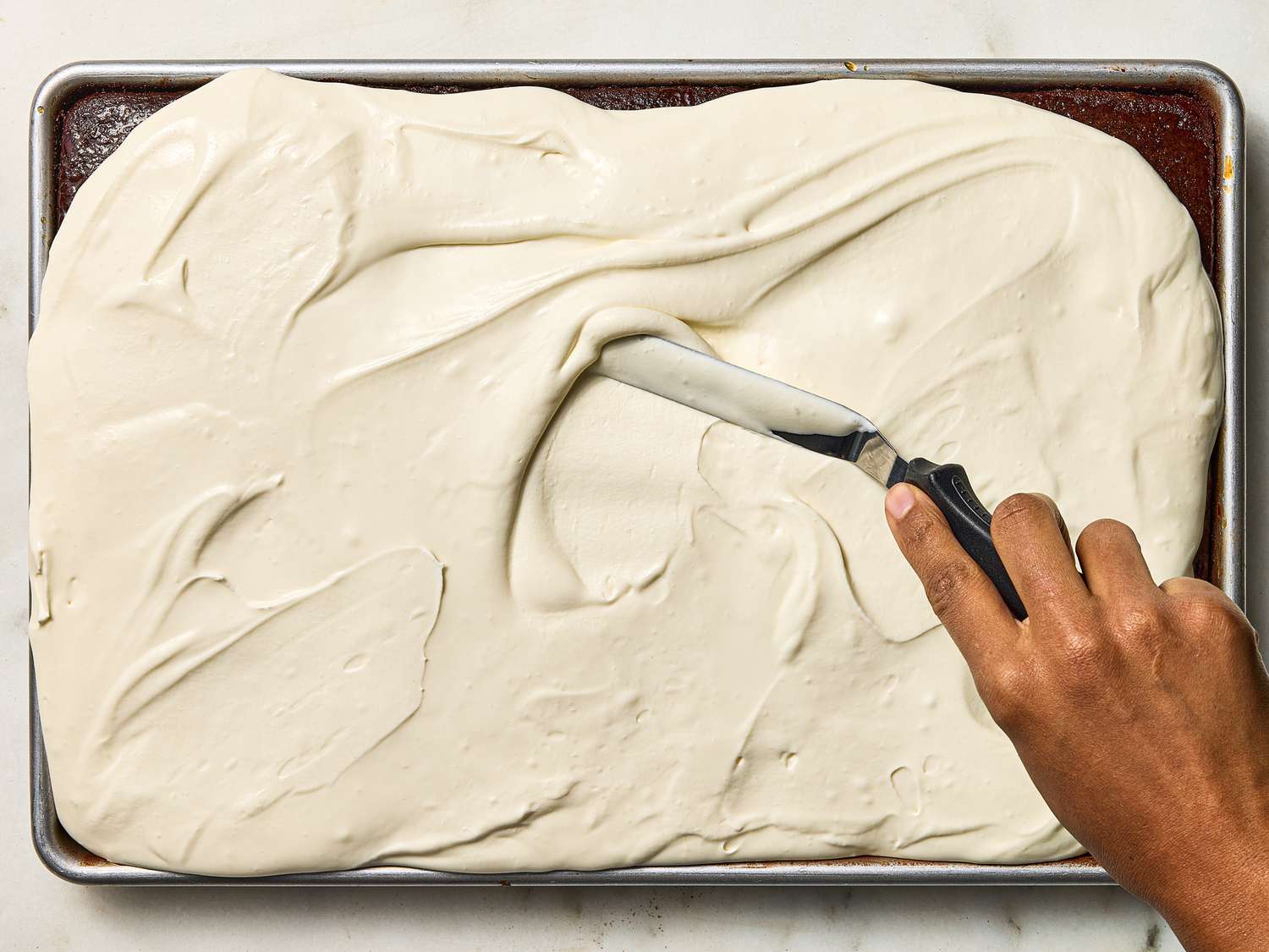 Smoothing frosting over cake with an offset knife