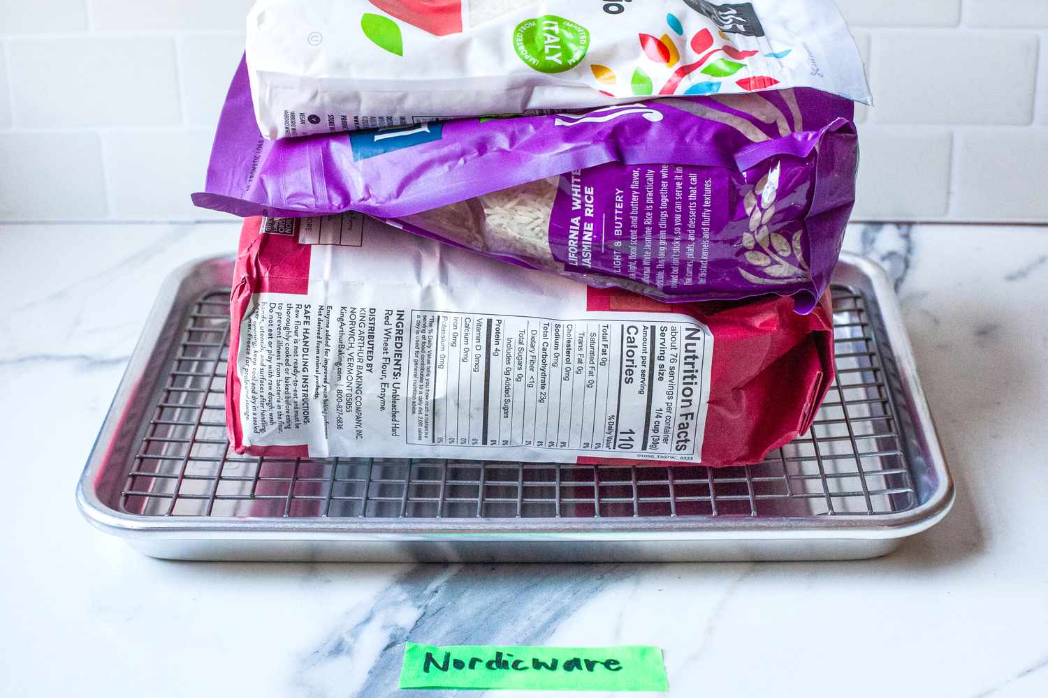 Baking supplies piled on the Nordic Ware Naturals Quarter Sheet with Oven-Safe Nonstick Grid to test its weight capacity