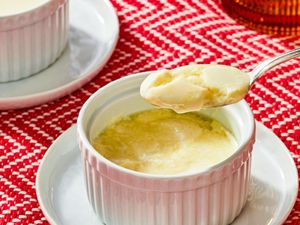 A serving of ginger pudding in a ramekin with a spoonful lifted out placed on a red patterned cloth