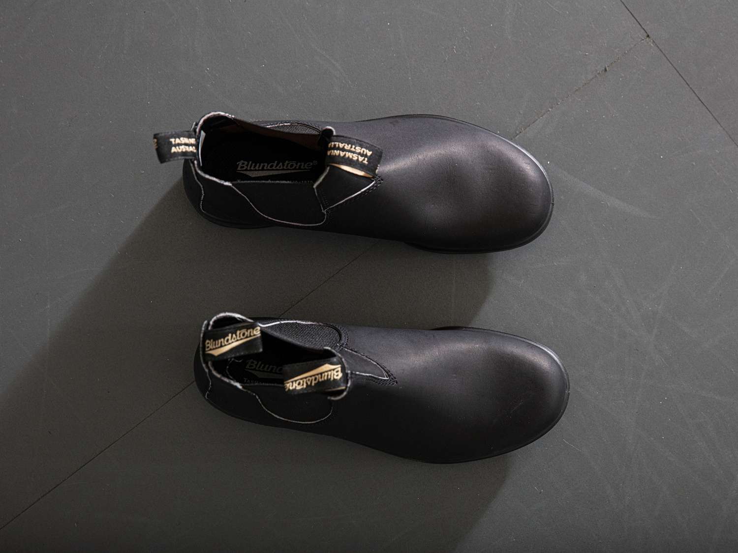Black Blundstone boots on a grey floor.