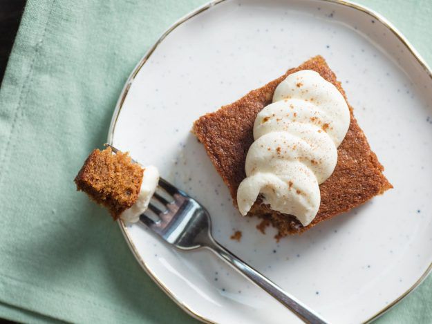 Square of gingerbread cake with cream cheese frosting on a plate