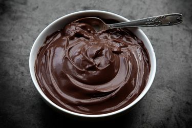 A bowl of chocolate pudding with spoon