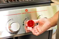 A person adjusts the temperature on the Weber Genesis E-325 Liquid Propane Gas Grill