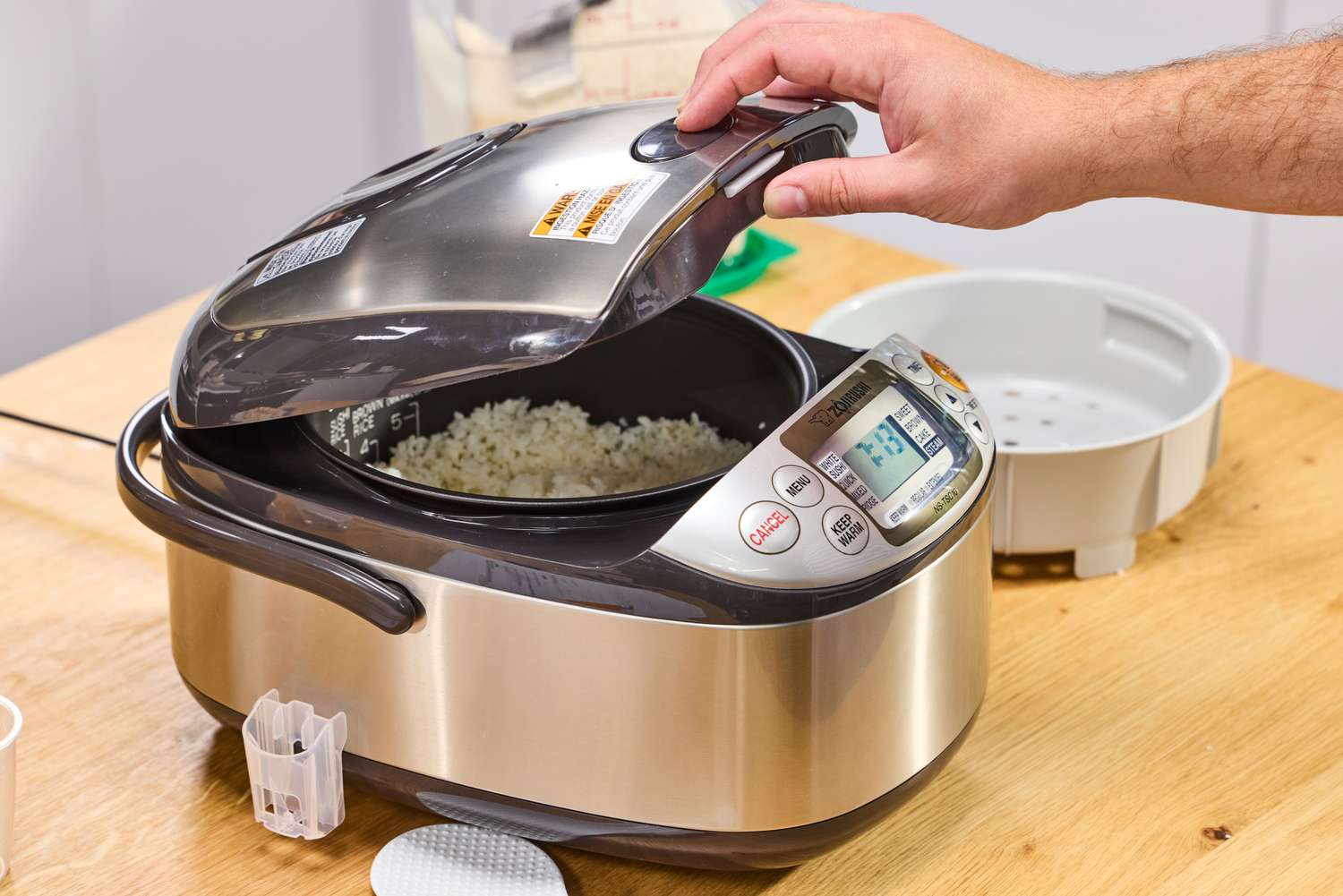 A person lifts the lid on the Zojirushi NS-TSC10 Miacom Rice Cooker and Warmer
