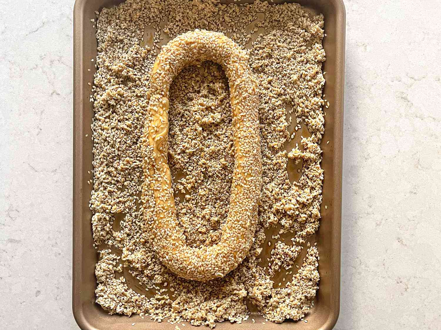Overhead view of dough being placed in sesame seeds