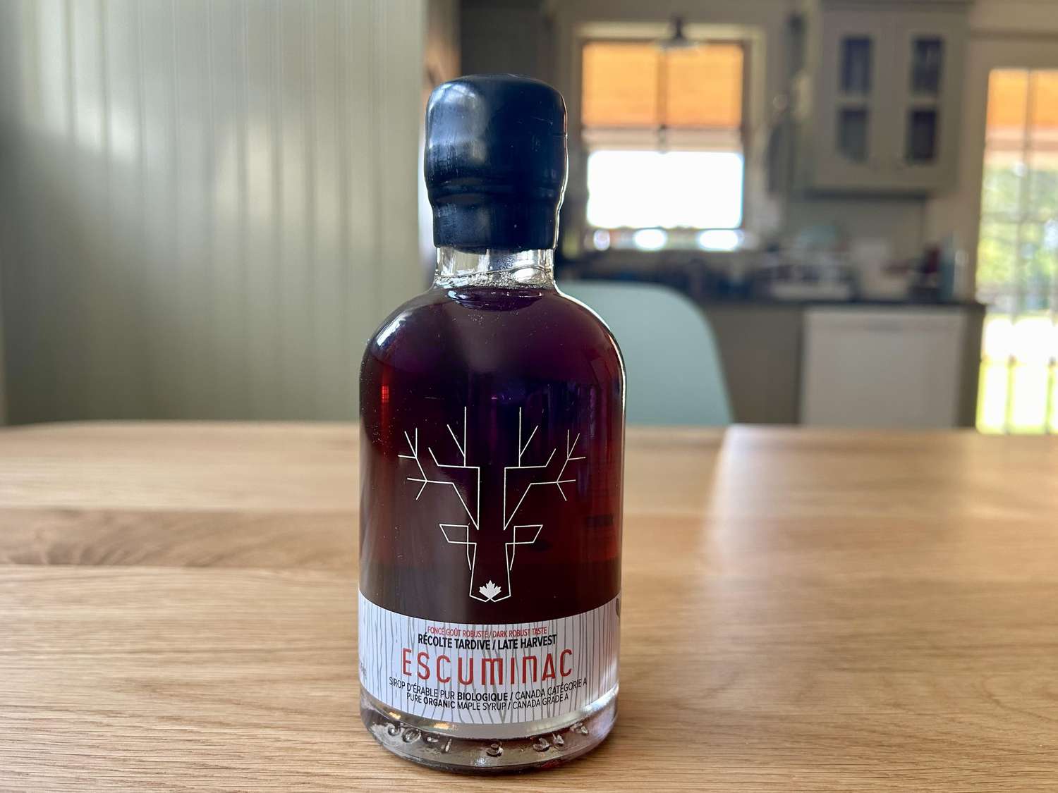 A bottle of Escuminac maple syrup on a kitchen table
