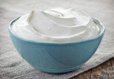 A small blue bowl full of sour cream. 