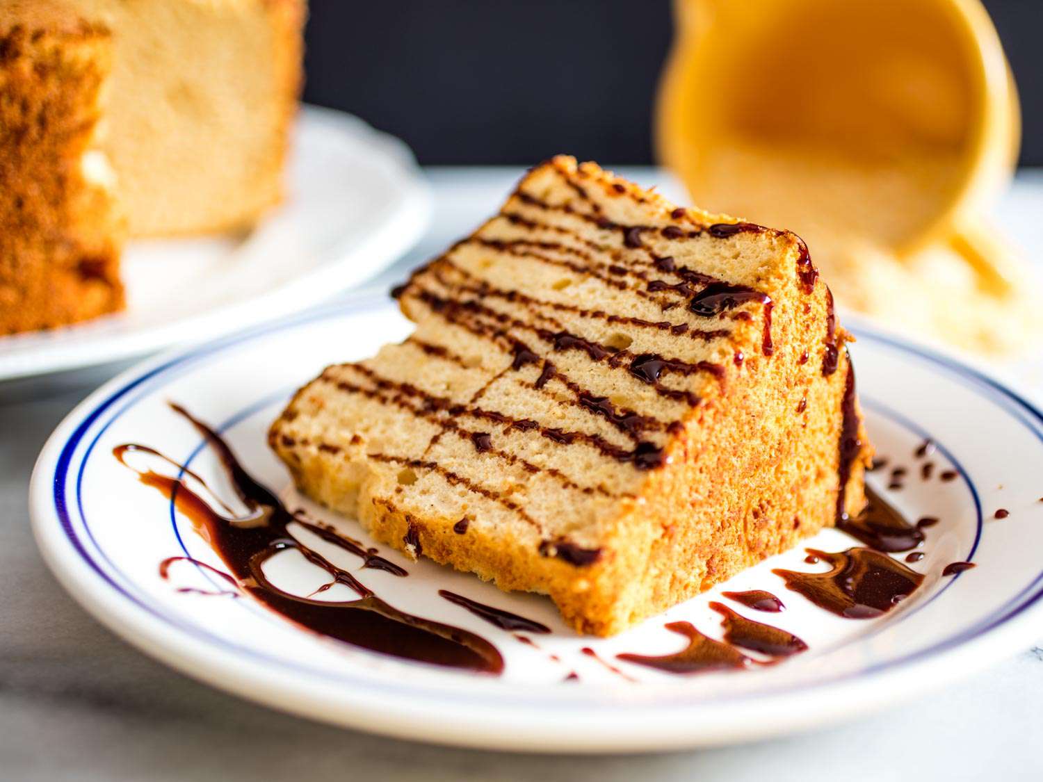 A plated slice of toasted sugar angel food cake drizzled with chocolate