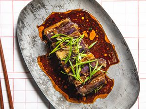 Overhead image of eggplant salad on a grey stoneware plate with chop sticks
