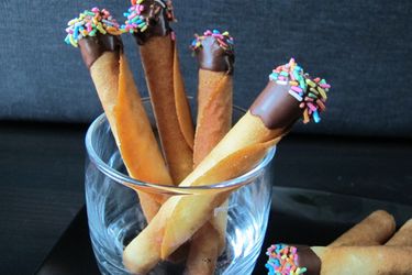 A highball glass holding a "bouquet" of 4 chocolate-dipped tuiles.