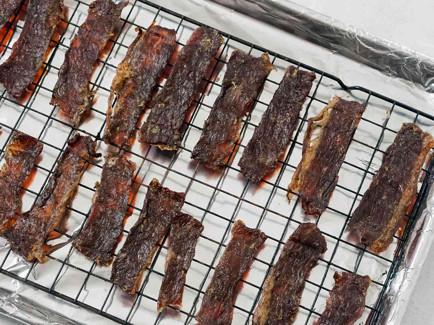 Dried beef on a rack in a foil-lined baking sheet, ready to be pounded into machaca.
