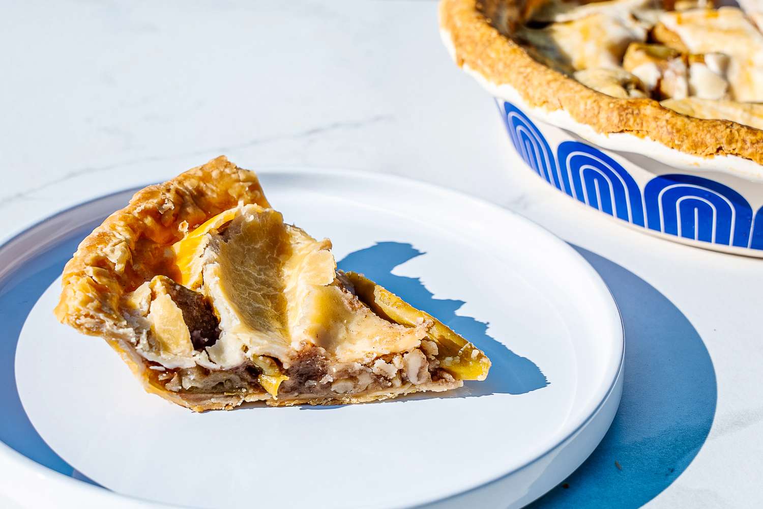 A slice of pie on a white plate next to a pie pan