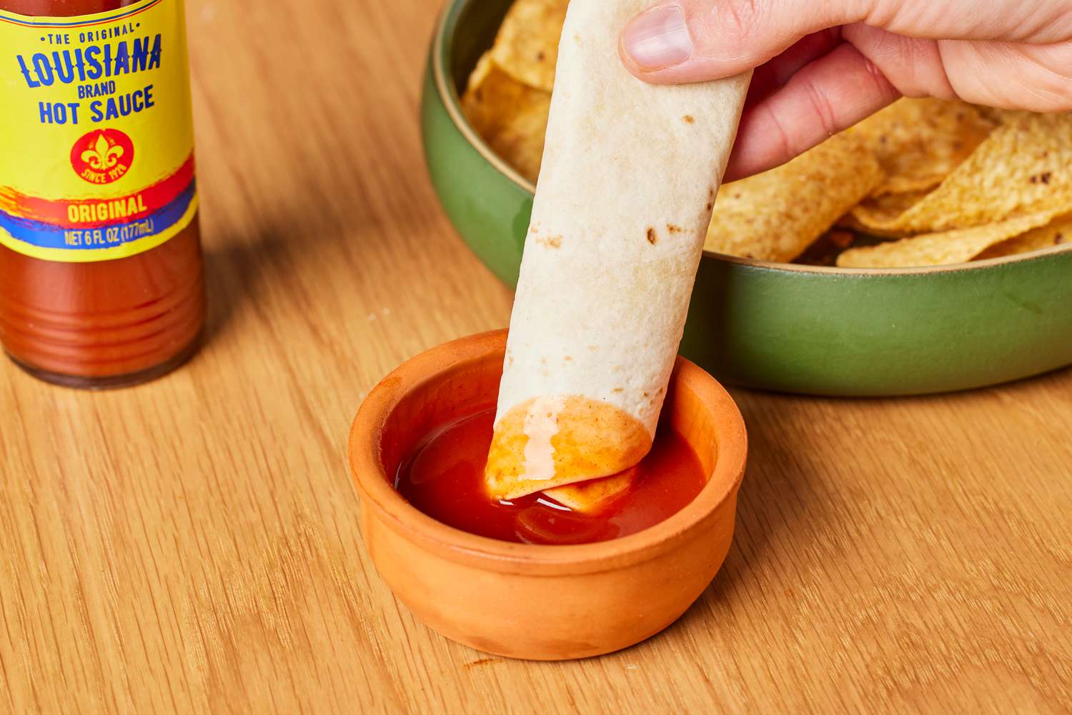 Person dipping tortilla in Louisiana The Perfect Hot Sauce