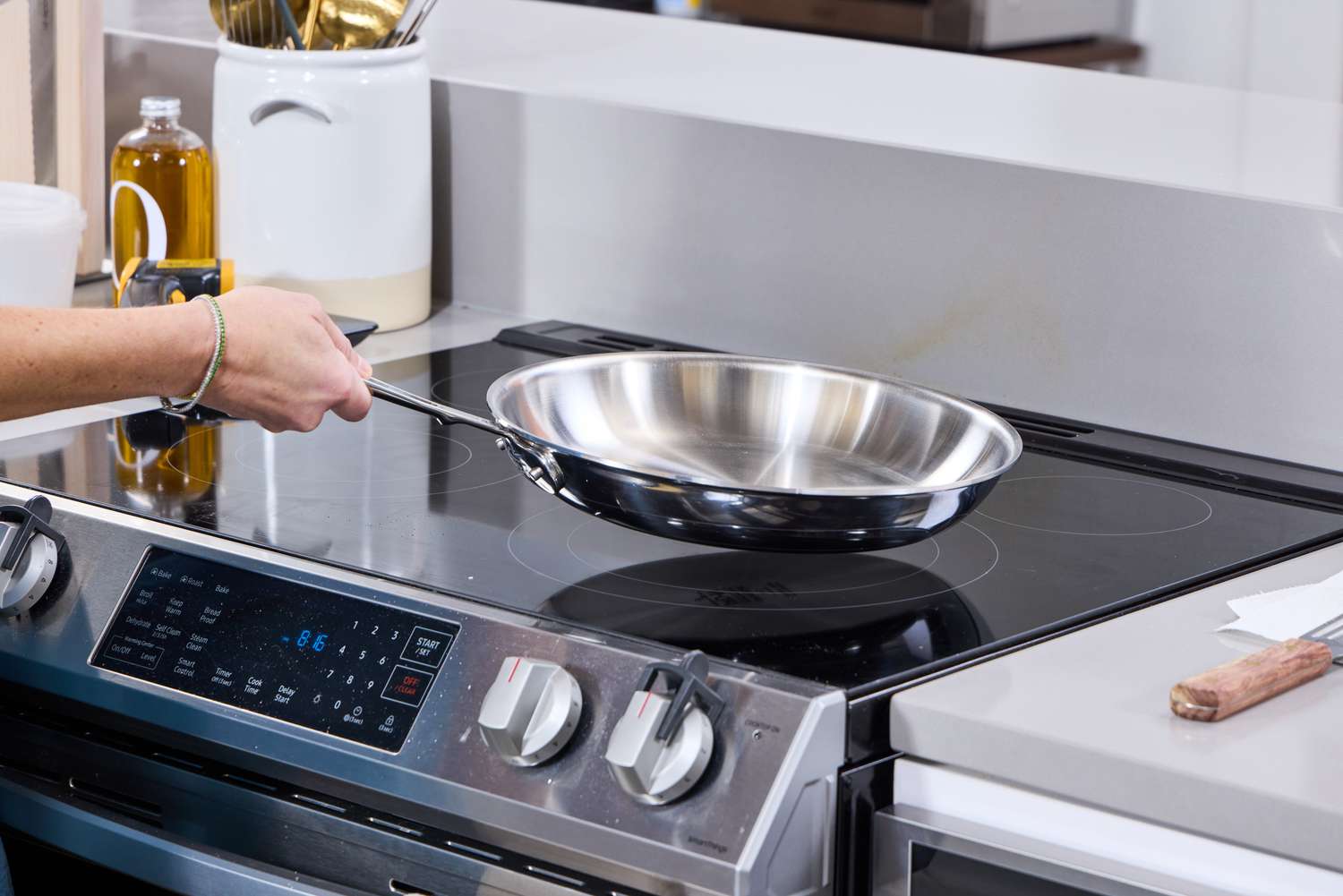 The All-Clad Stainless steel skillet being placed on an induction cooktop.