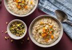 vanilla rice pudding in two bowls topped with dried apricots and pistachios
