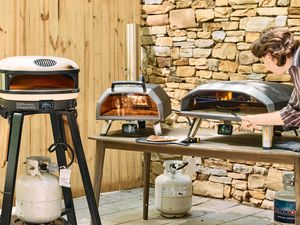 Three outdoor pizza ovens on a patio.