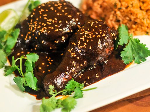 Two chicken drumsticks covered in mole poblano.