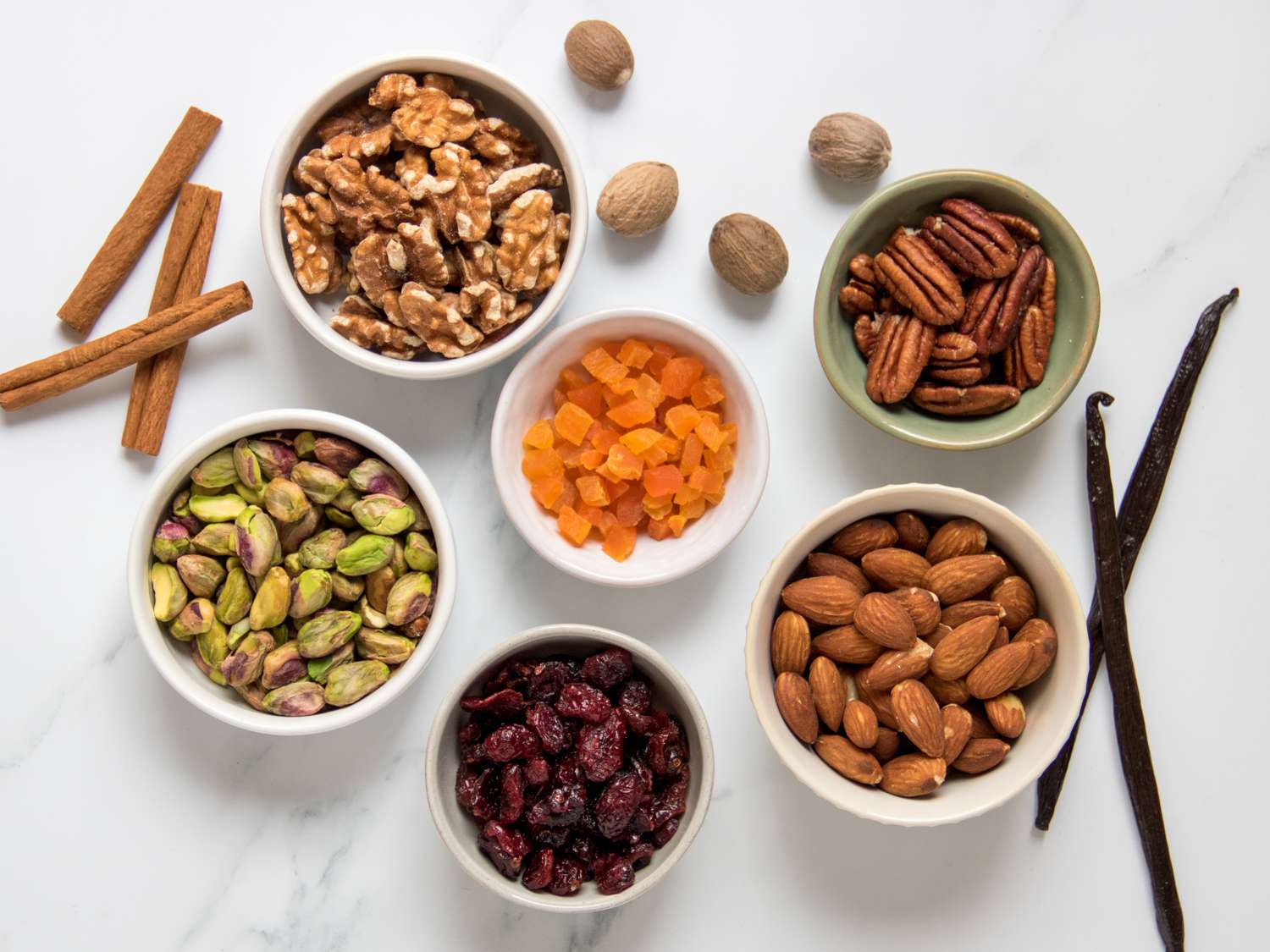 flat-lay of mix-in options for rice pudding, an assortment of dried fruits and nuts and spices 