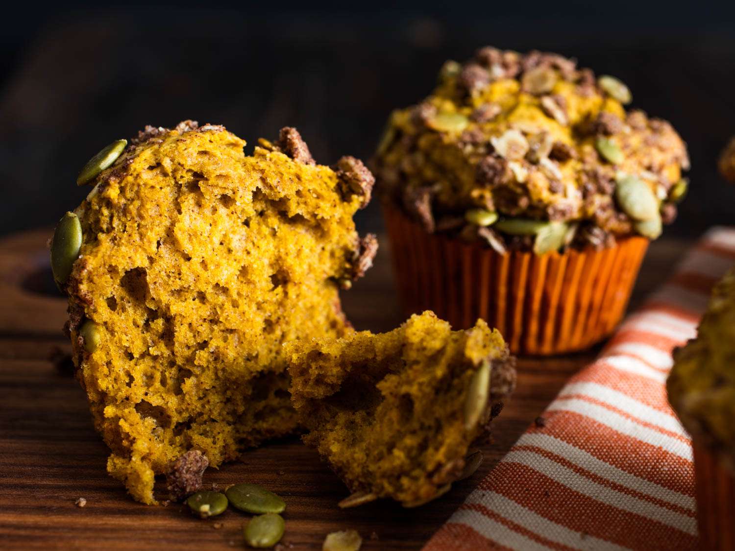 Close-up of a pumpkin streusel muffin that's been torn in half to reveal its tender yellow-orange crumb.