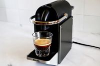 A singleserve coffee machine brewing espresso into a glass cup