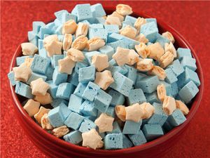 A bowl full of blue cubed and orange star-shaped crispy cereal marshmallows.