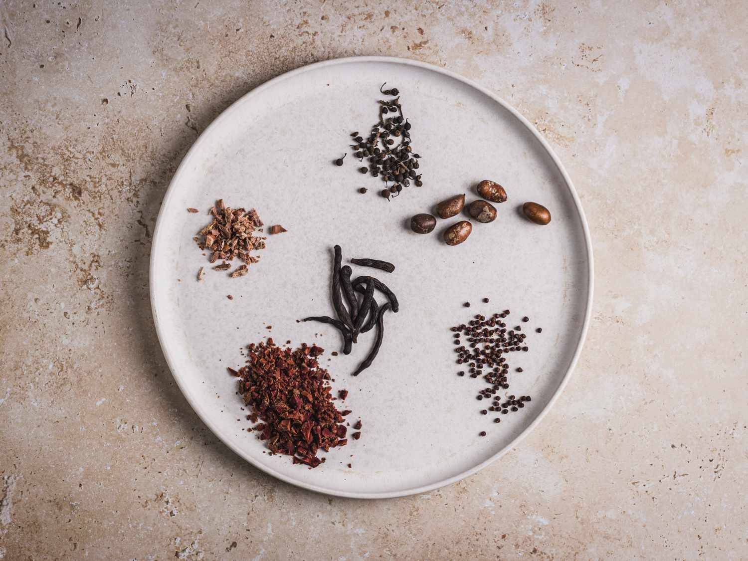 Erhe (calabash nutmeg), urheri/uda (grains of Selim), alligator pepper (grains of paradise), umilo (cocoplum), and gbafilo (rough-skinned plum) on a white plate.