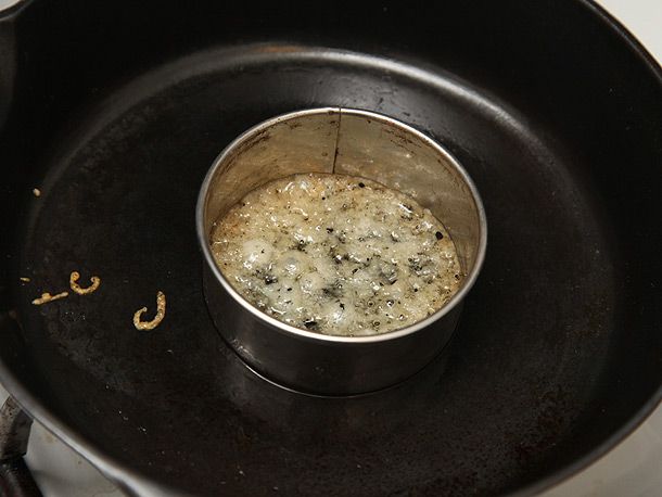 Bubbling melted cheese inside a ring mold on a cast iron skillet.