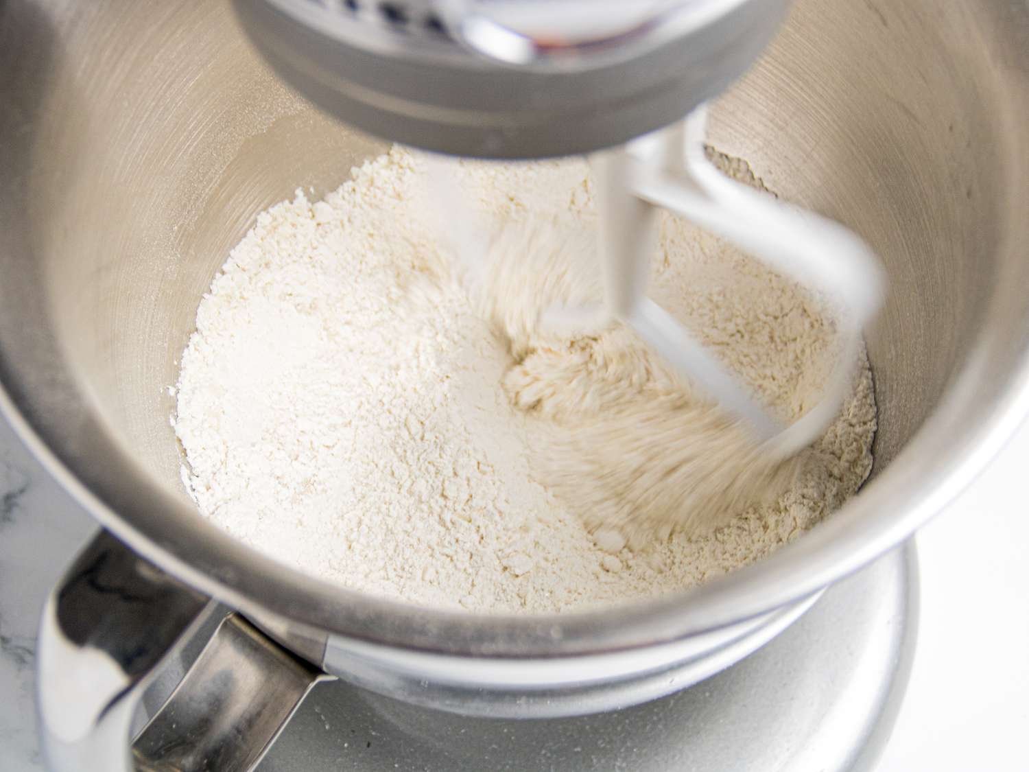 Flour being mixed in a stand mixer bowl
