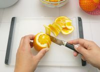 a person slicing off the rind of an orange