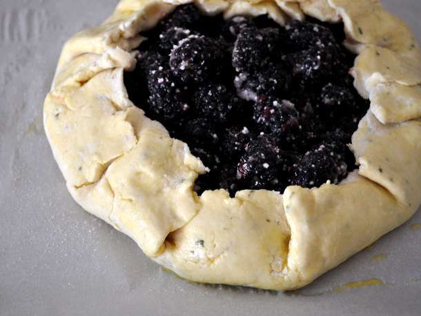An assembled blackberry thyme galette on a parchment-lined baking sheet, ready to go in the oven.