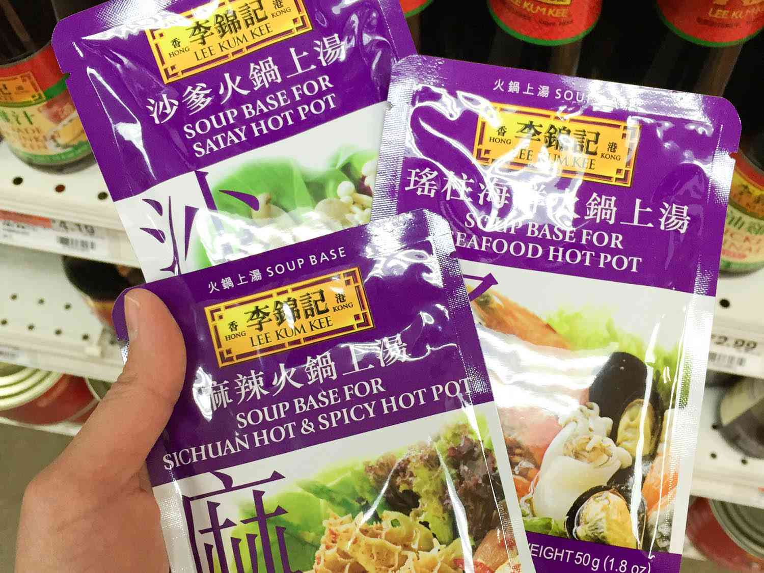 Hand holding packages of ready-to-use hot pot broth at grocery store.
