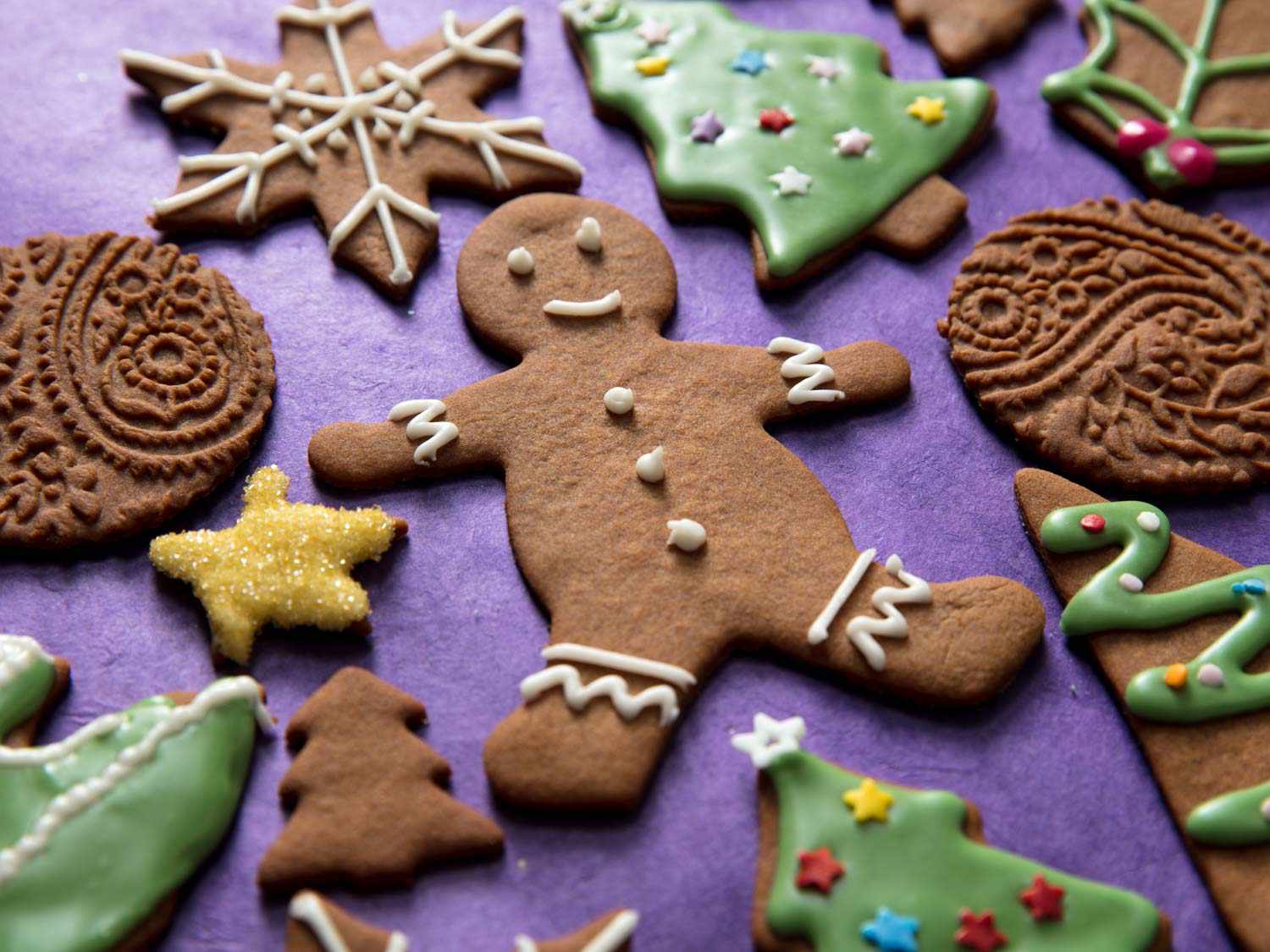 Gingerbread cookies decorated with royal icing on a purple surface.