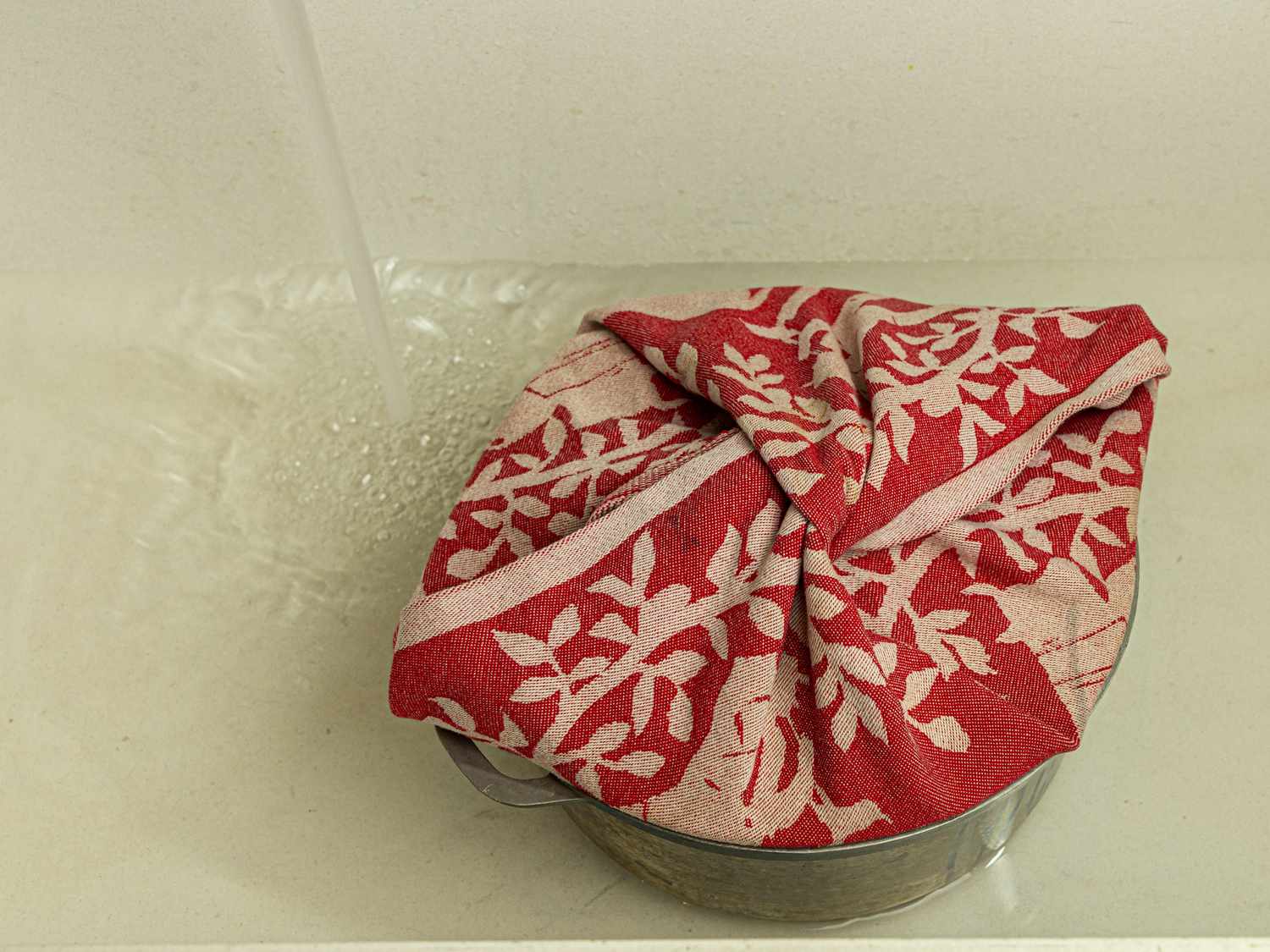 Overhead view of pot with lid in a sink with water