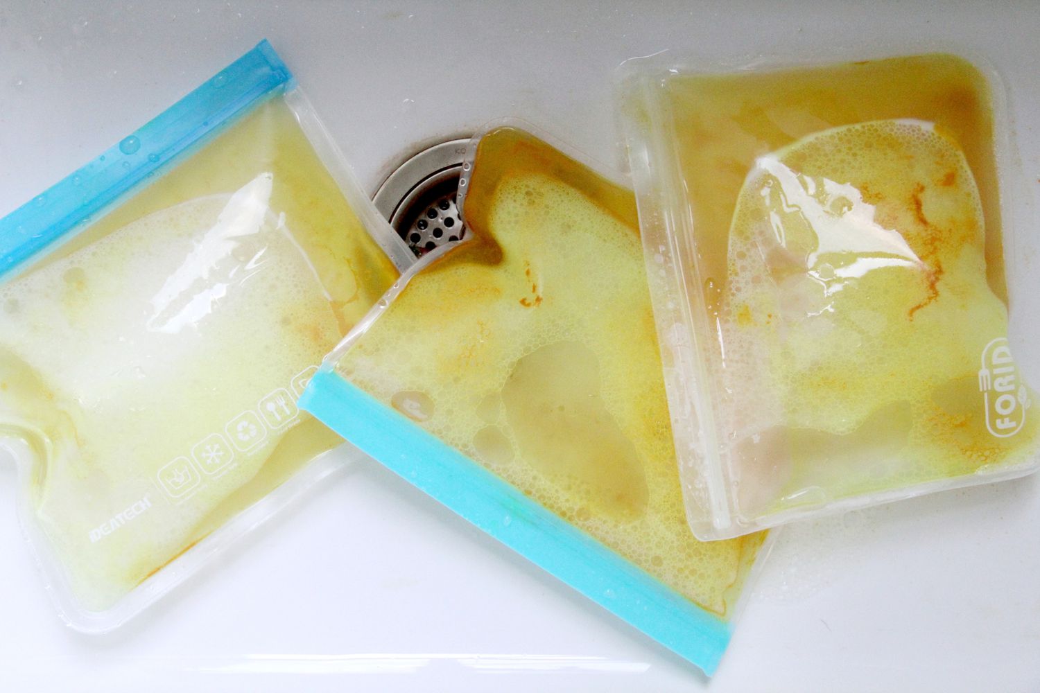 Reusable food bags stained with turmeric in a kitchen sink