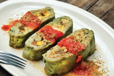 Three slices of Brazo de Reina topped with spoonfuls of tomato frito. 