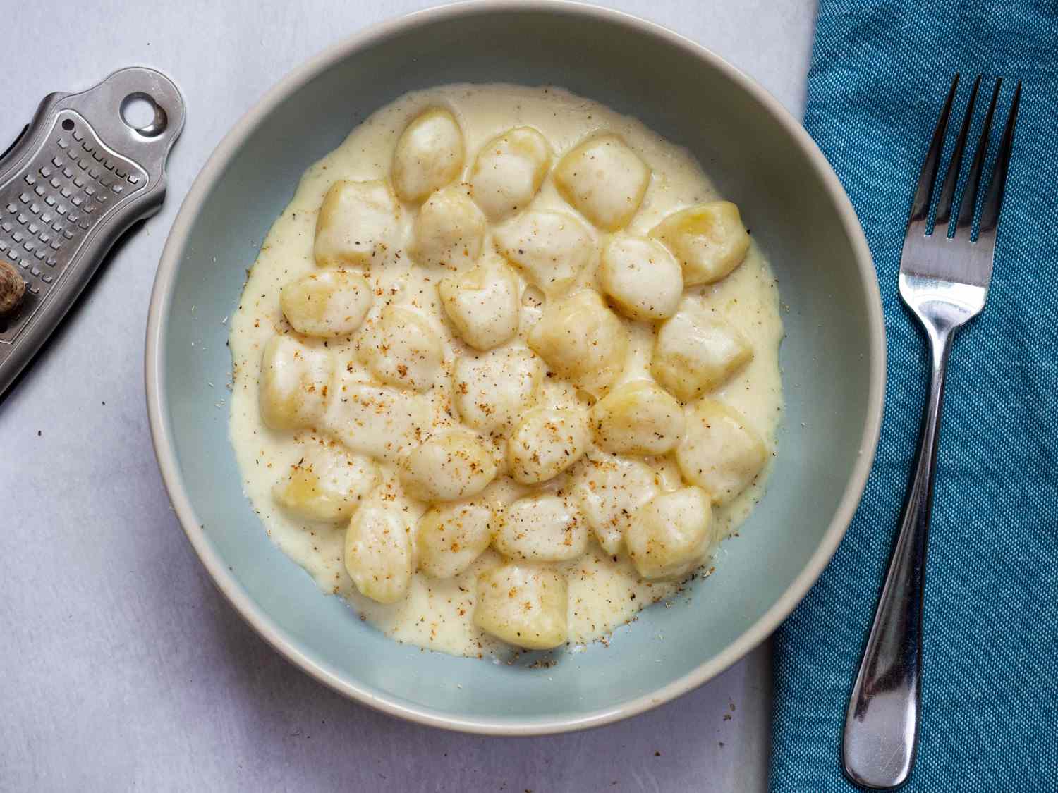 Gnocchi in a cheese sauce resting in a blue bowl