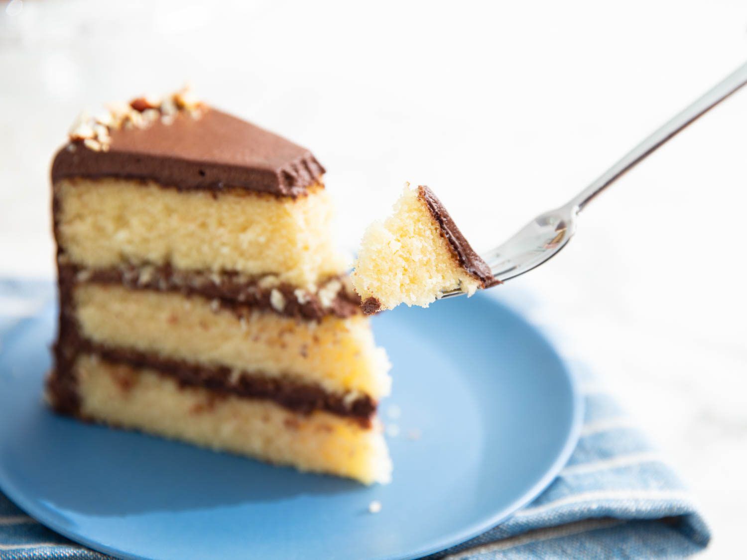 A slice of three layer yellow cake with chocolate frosting