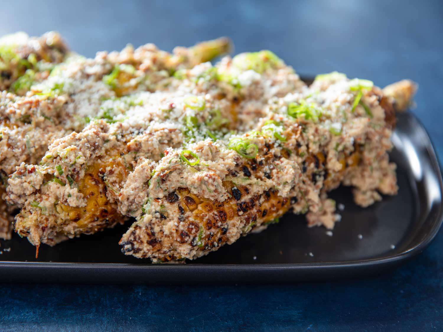 Elotes with XO sauce on a platter.