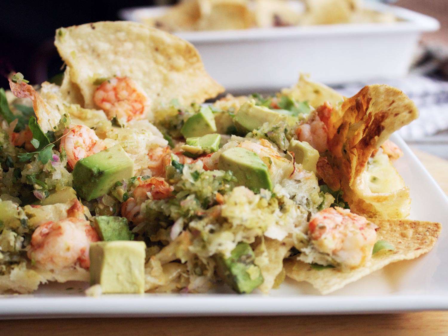 Profile closeup of Shrimp Nachos With Tomatillo Salsa, served on a square white plate.