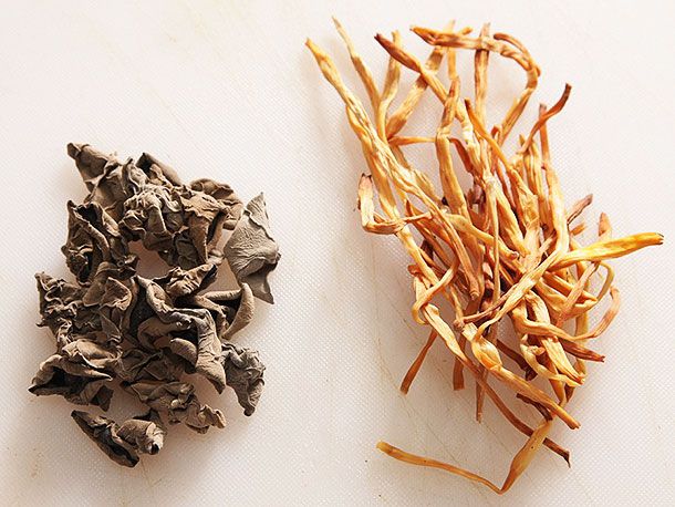 Dried wood ear fungus and daylilly buds on a white surface. 