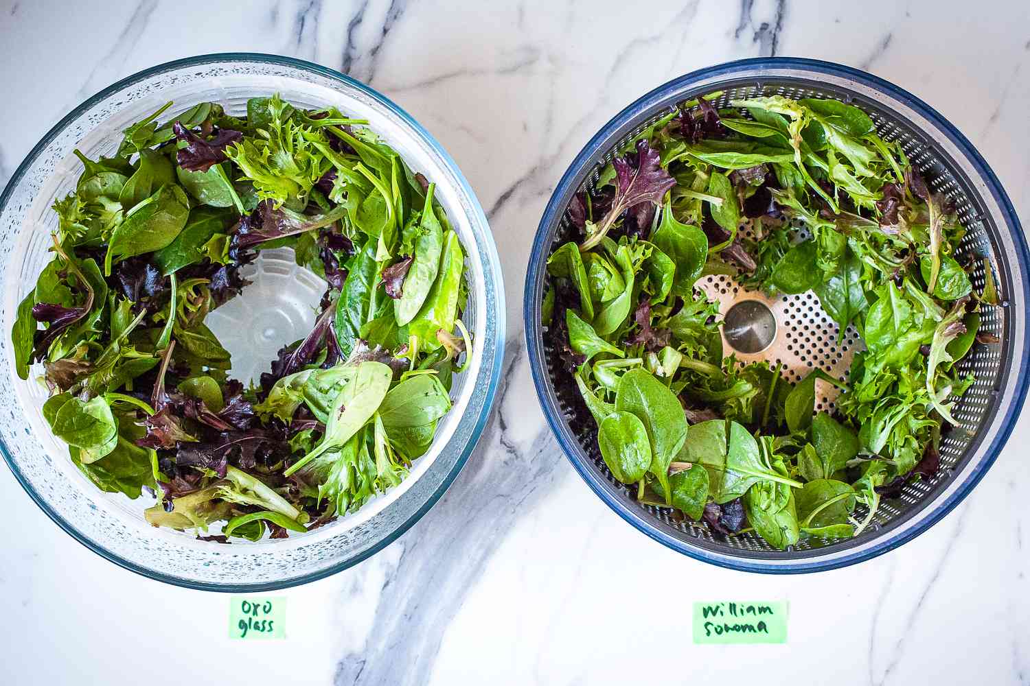 two salad spinner next to each other with mixed greens inside