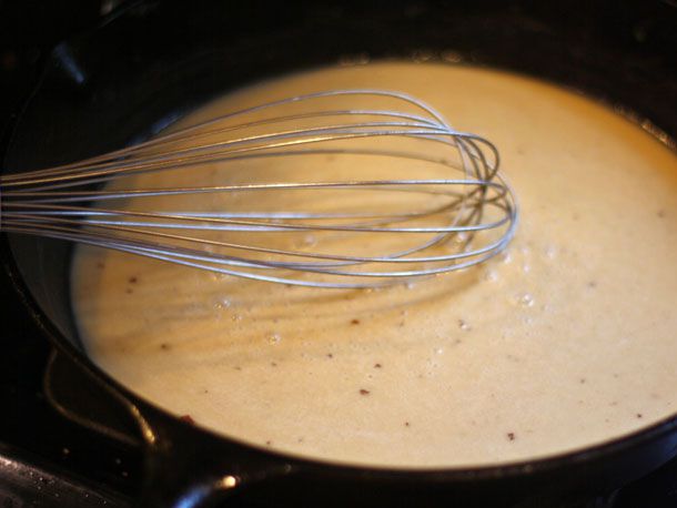 Whisking cheese sauce in a skillet.