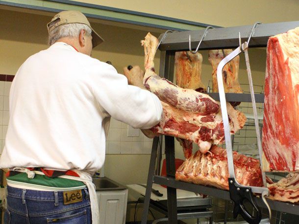 butcher in shop working with raw carcass