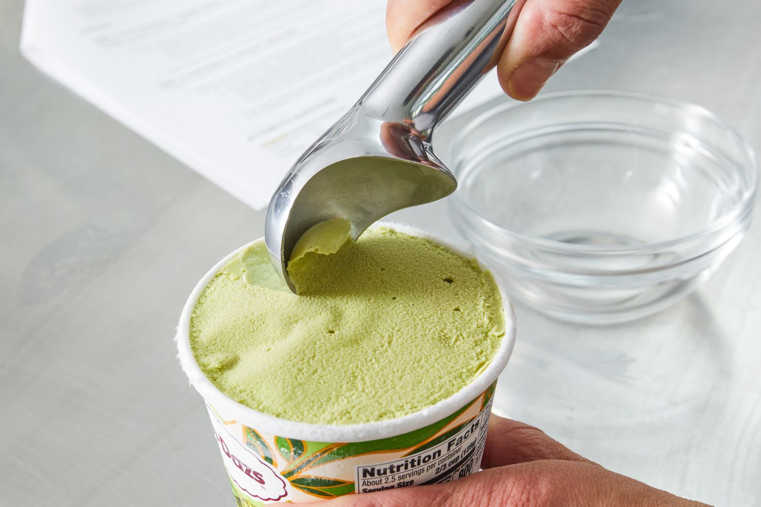 a person using an ice cream scoop to scoop pistachio ice cream